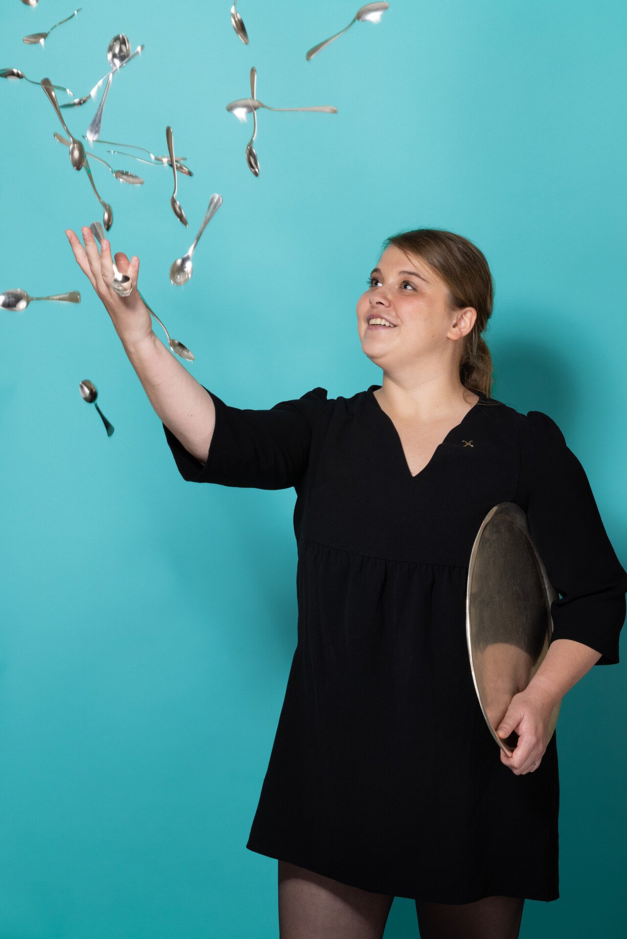 Woman throwing spoons against a blue background