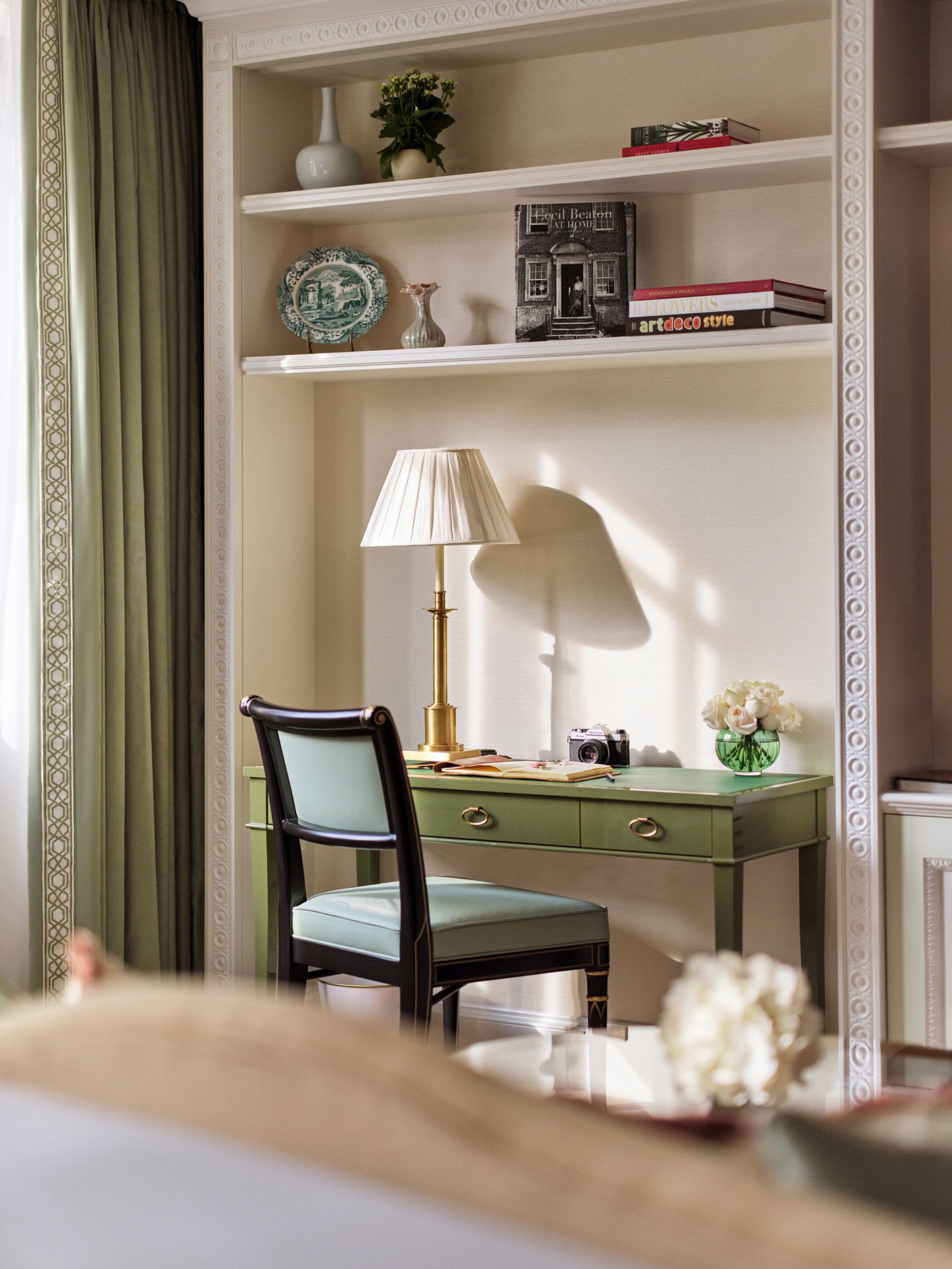 The Executive Park View Room at The Dorchester, showcasing a built-in writing desk with a green leather surface, elegant shelving styled with books and ceramics, and natural light streaming through nearby windows.