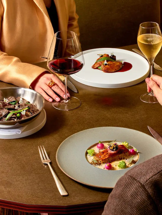 People enjoying a dinner with wine and elegantly plated dishes at a cozy restaurant table