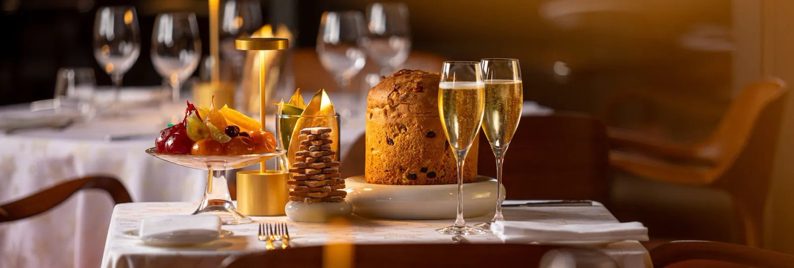Festive table setup with glasses of champagne, panettone, candied fruit and biscuits at Il Giardino Ristorante at Hotel Eden, Rome
