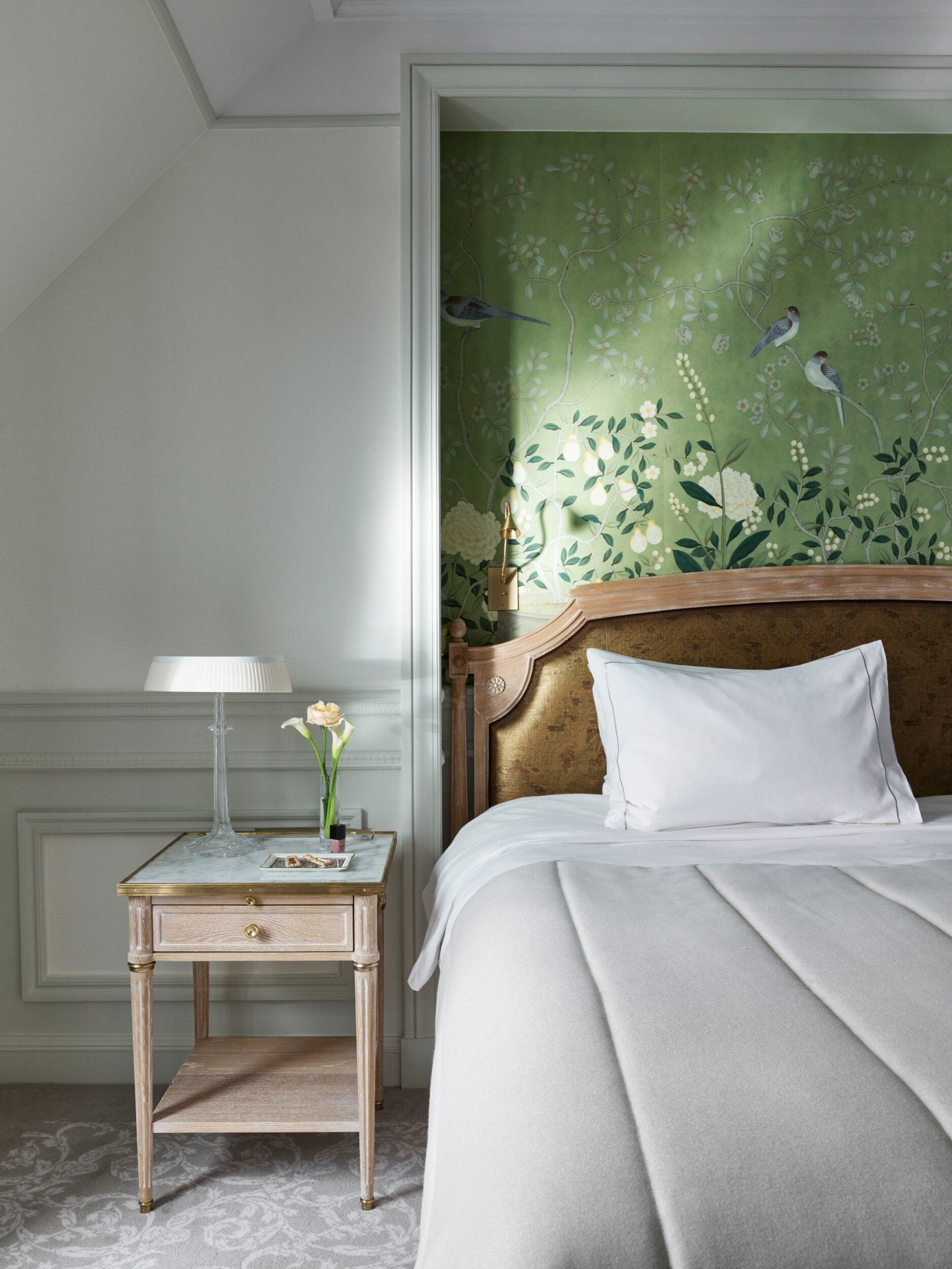 Portrait d’une chambre exécutive avec un mur peint à la main vert et une table d’appoint en bois avec un plateau en marbre. Au Meurice, Paris.