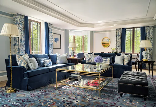 A sophisticated suite with comfortable seating in deep blue and paler tones