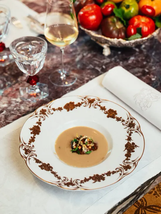 Empty plate with food, wine glass, fruit bowl, and napkin on a marble table.