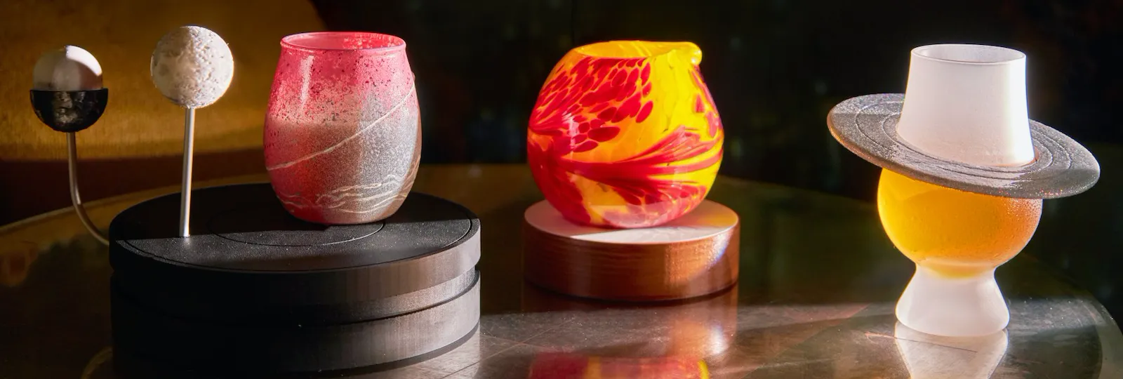 Decorative cups and hats on a reflective surface with a dark, blurred background.