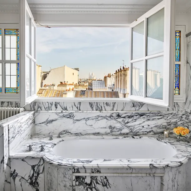 Banheiro de mármore com janelas abertas com vista para o horizonte de Paris em suíte júnior executiva no Le Meurice, Paris.