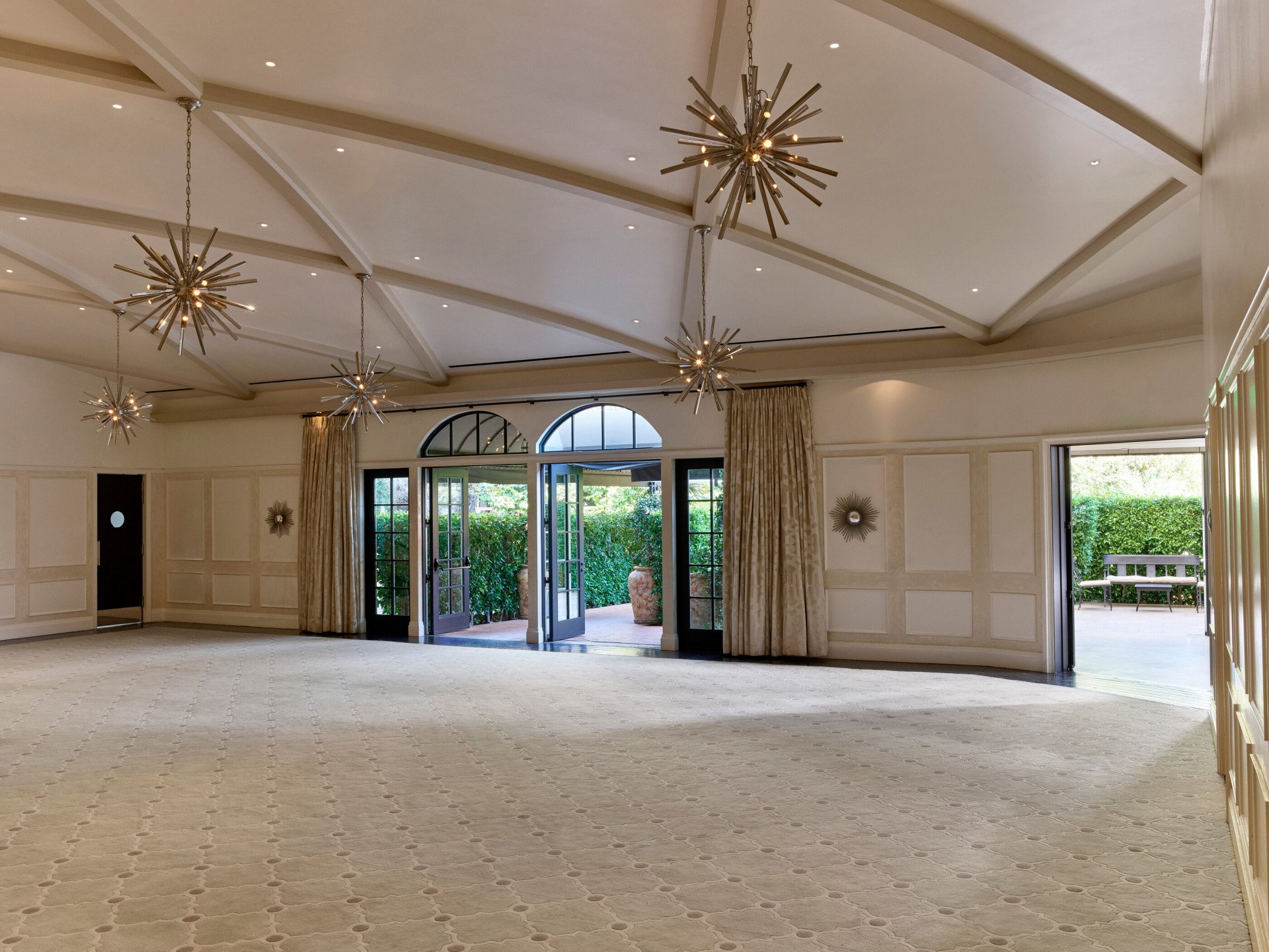 Garden Ballroom event space at Hotel Bel-Air with star-shaped chandeliers across the ceiling and natural light from the entrance doors. 