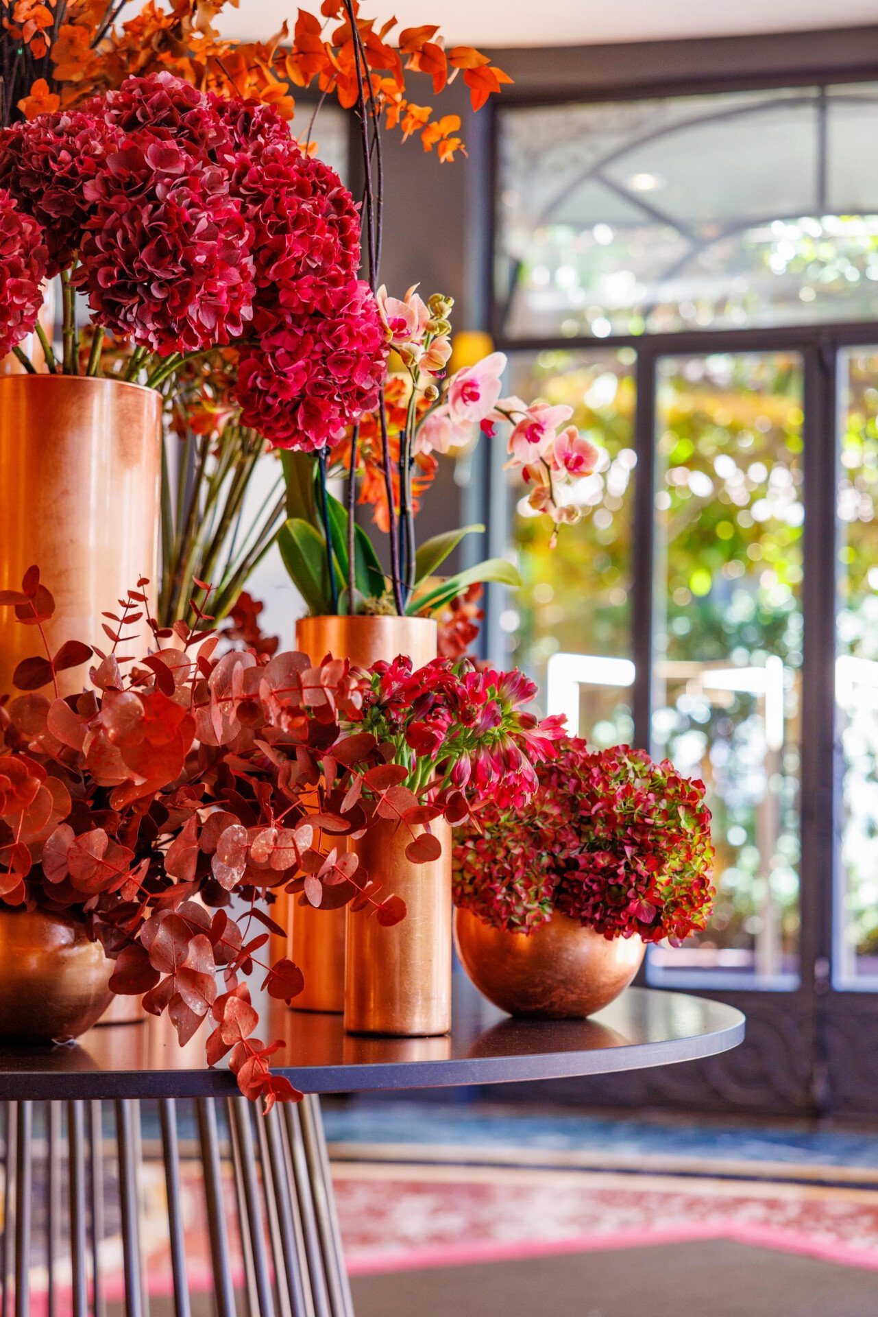 Fiori dai colori sui toni del rosso posizionati sul tavolo tondo all'ingresso