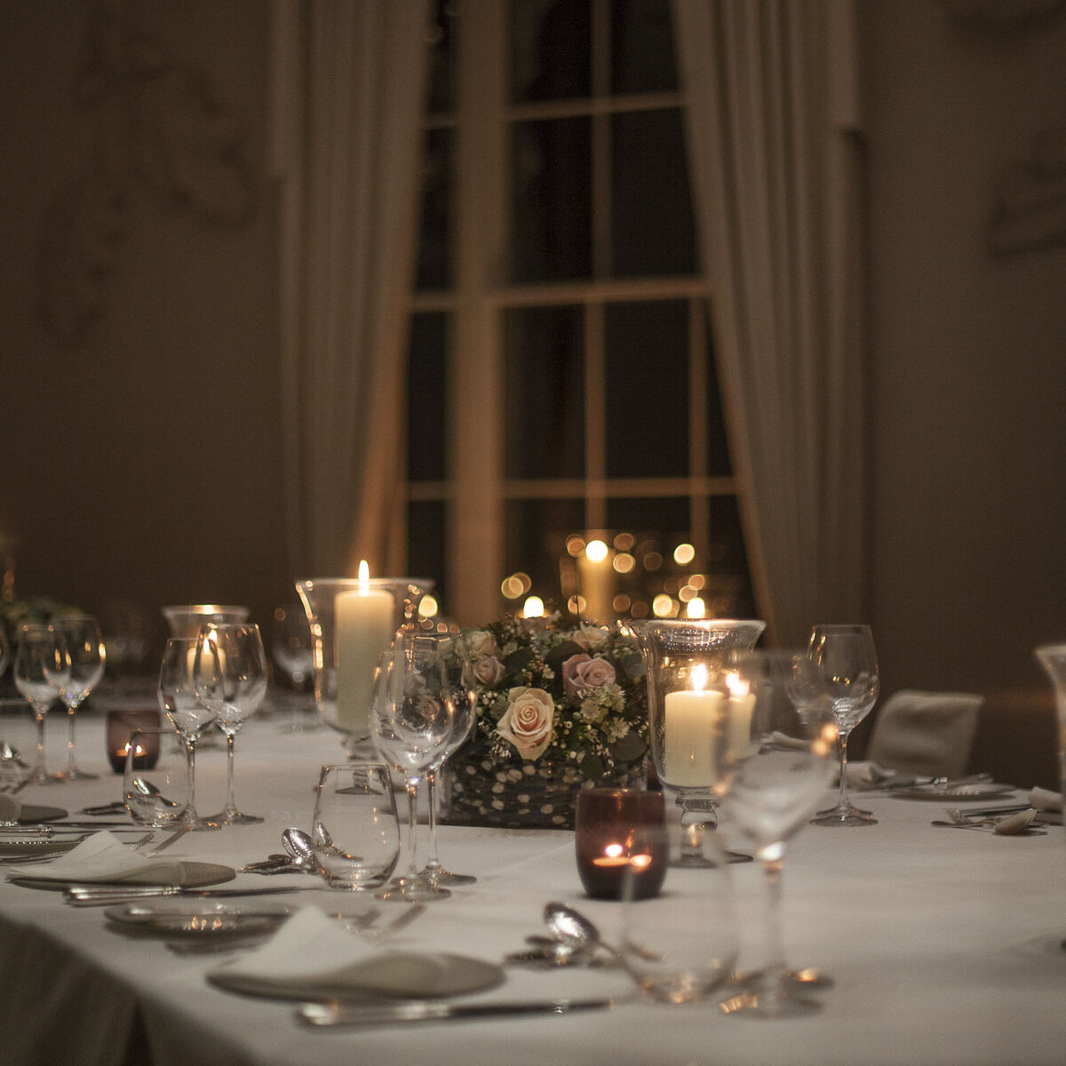 Candlelit dinner table with rose centrepiece set for an evening event at Coworth Park