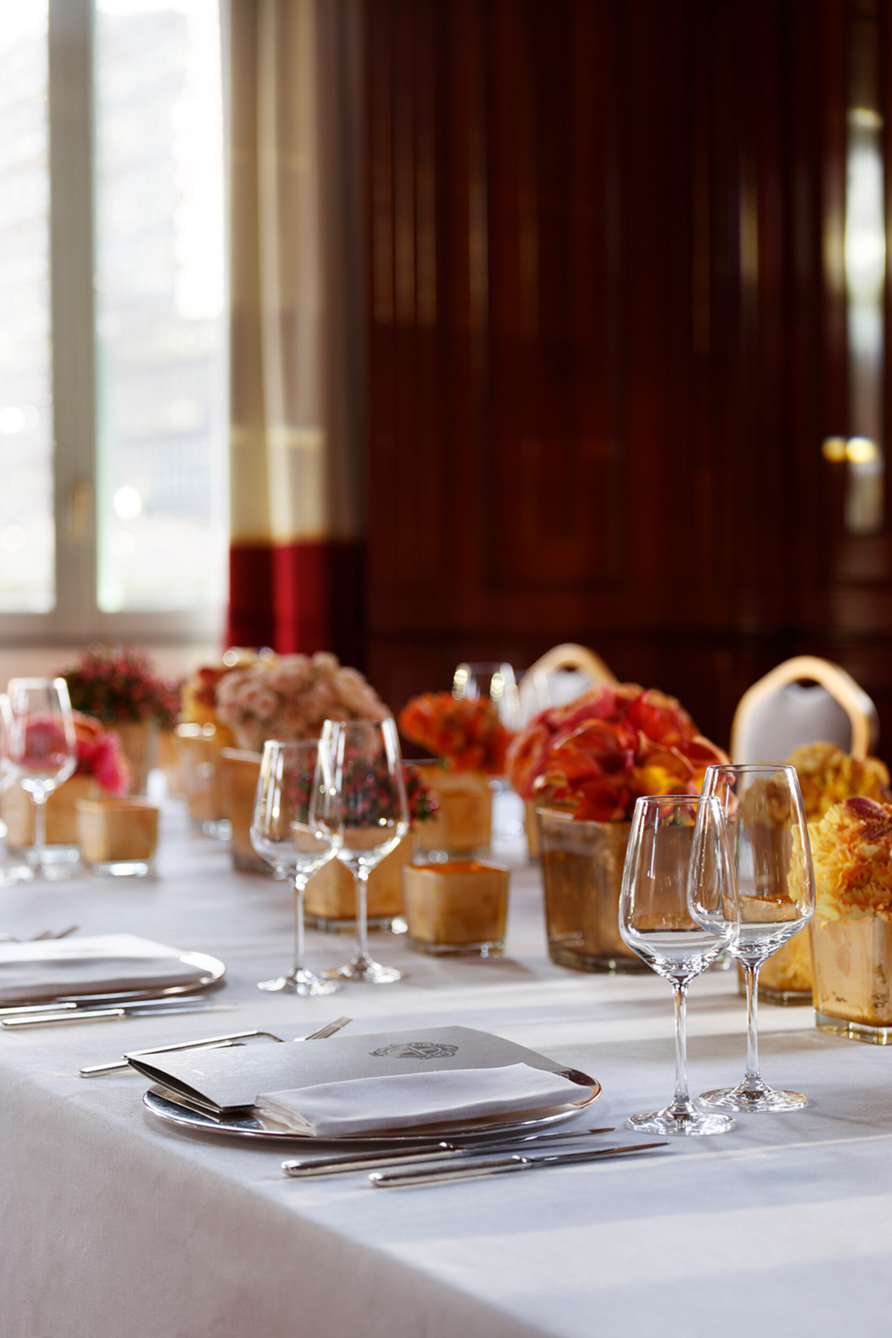 A close-up of a table laid for dinner in our ‘Club Principe’ events space. The table features several centrepieces with flowers in shades of orange.