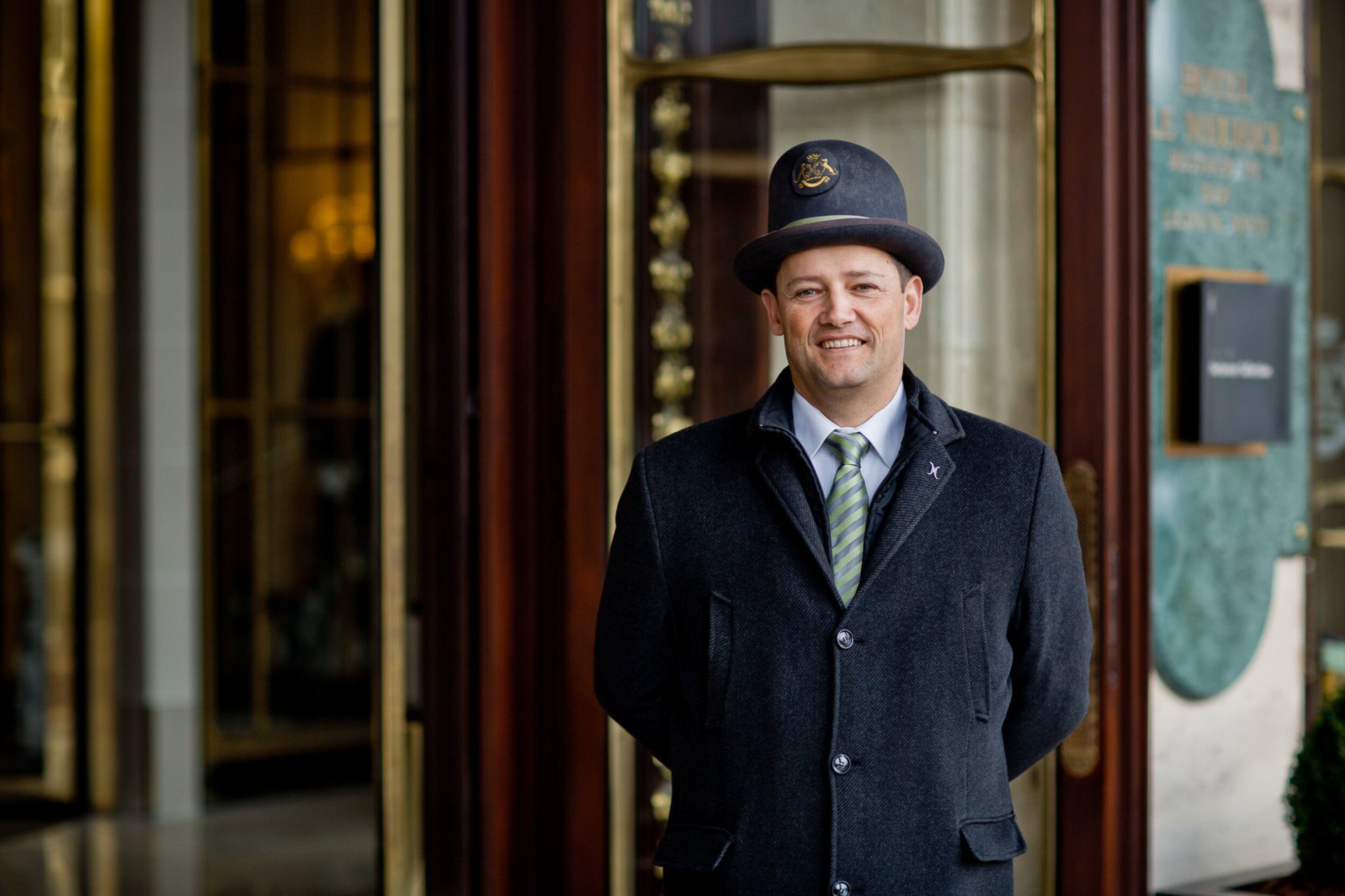 Cette photo représente un voiturier souriant devant la porte principale du Meurice, Paris