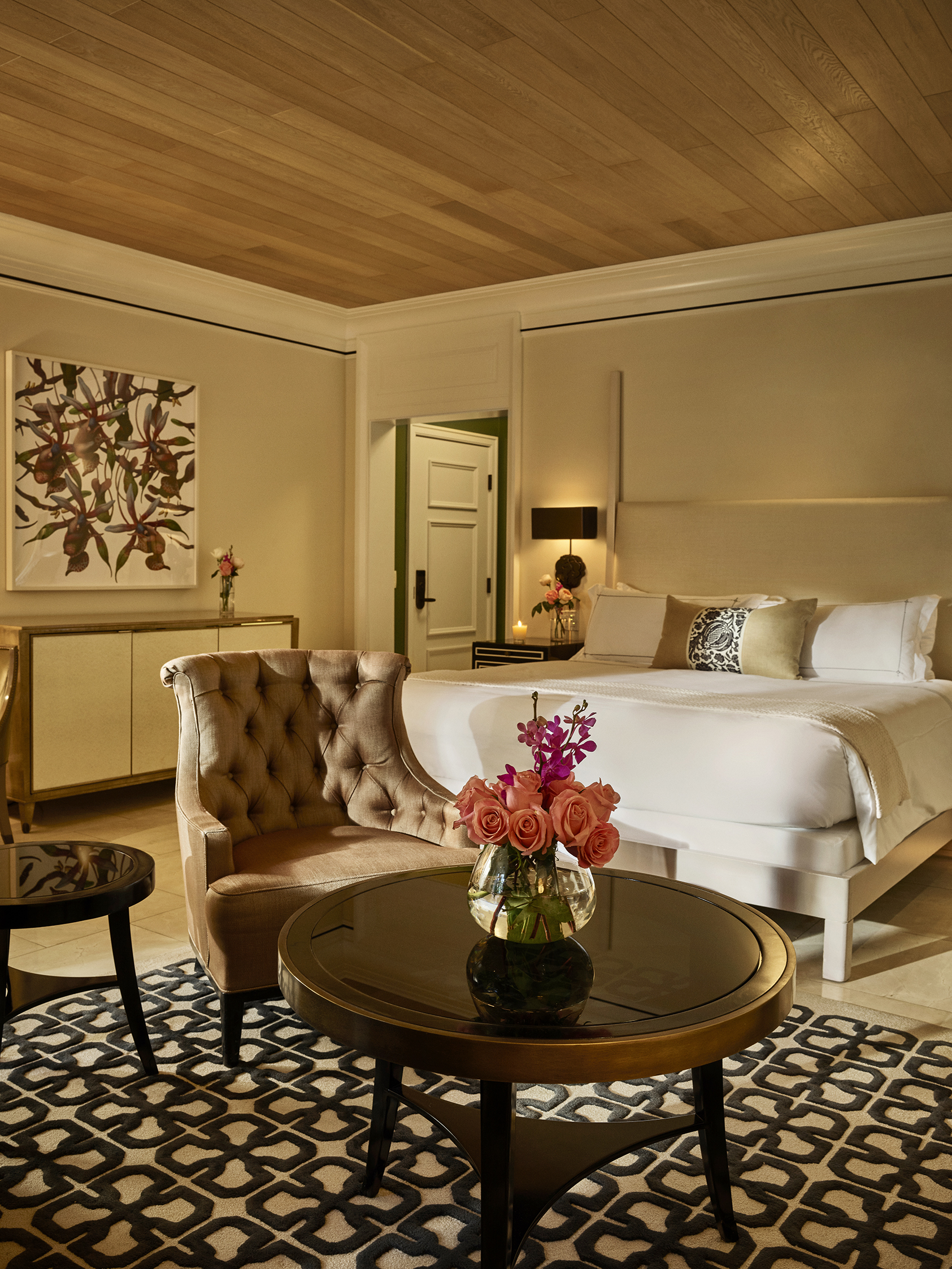 Junior suite at Hotel Bel-Air highlighting the sitting area with a small table and bouquet of flowers perched in front of the king size bed. 