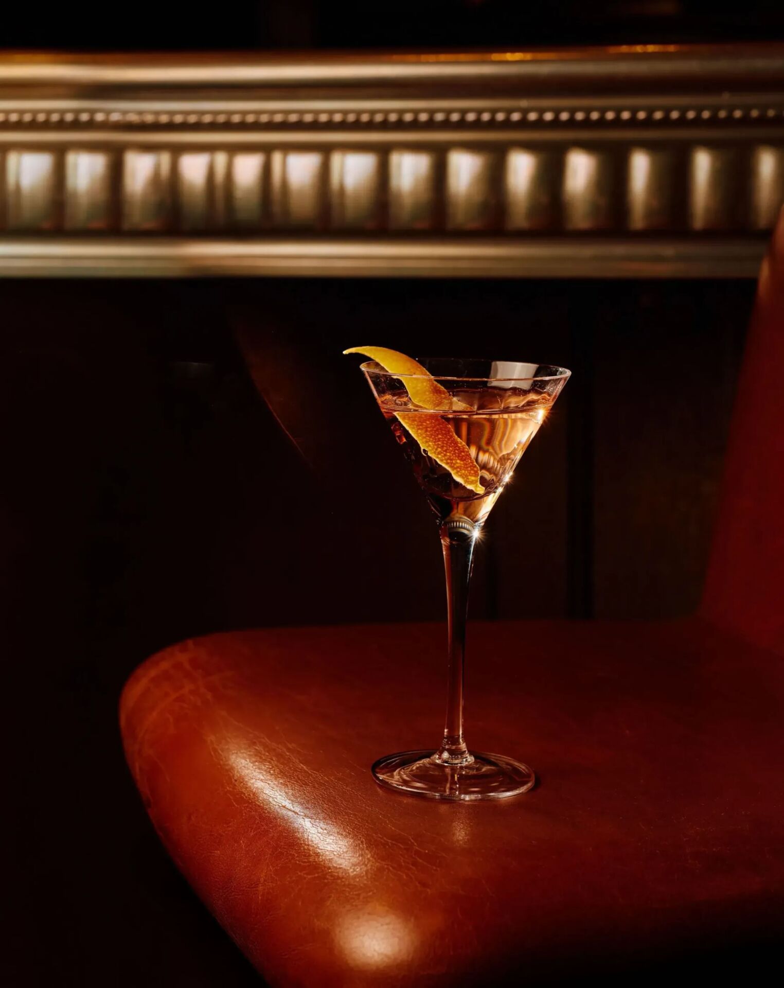 Signature Martini at The Grill at The Dorchester, elegantly presented in a classic stemmed glass and garnished with a lemon twist, set against the restaurant's warm leather seating and ambient lighting.