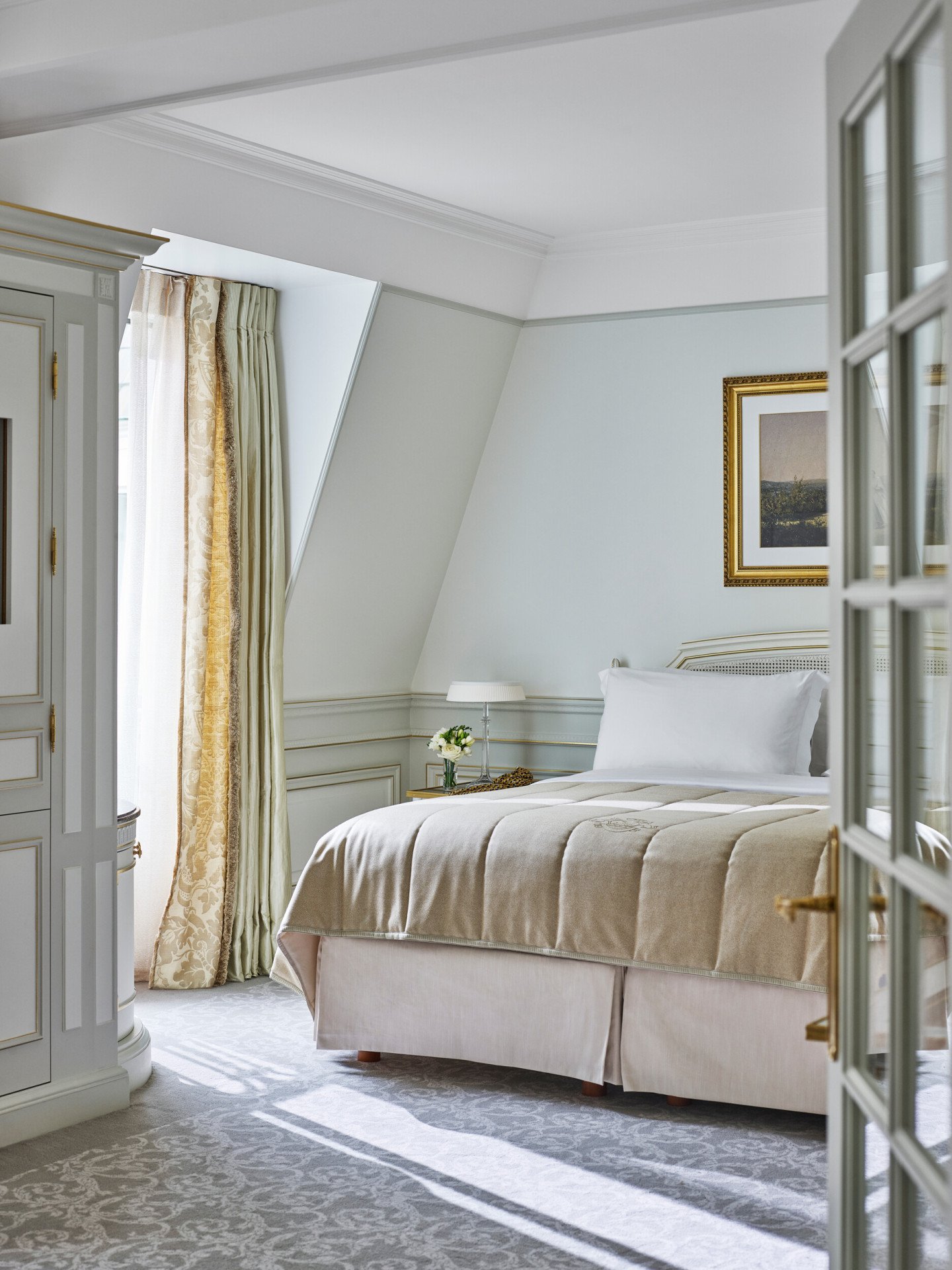 Quarto de uma suite júnior em tons de verde claro e bege no Le Meurice, Paris.