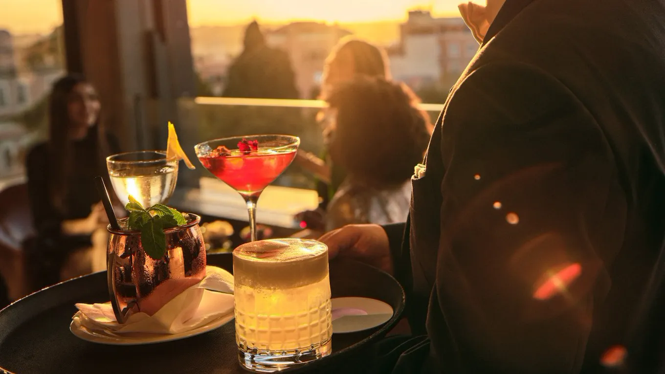 Cameriere che ha 4 cocktail diversi su di un vassoio a Il Giardino Bar