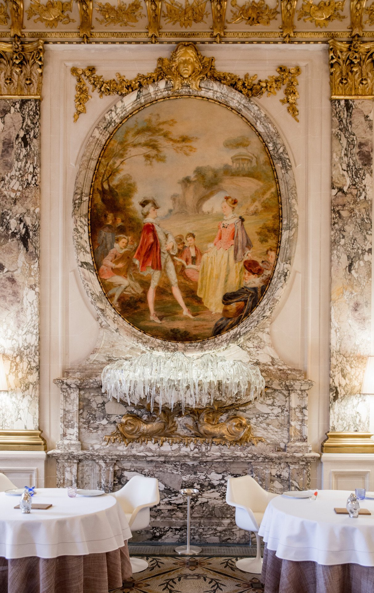 Retrato da escultura mural de vidro com mesas postas de cada lado no Restaurante Le Meurice Alain Ducasse, no Le Meurice, Paris.