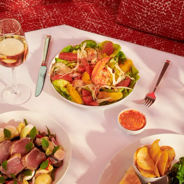Foto de um almoço no La Terrasse Montaigne com sandes de taco, duas saladas e um copo de vinho.