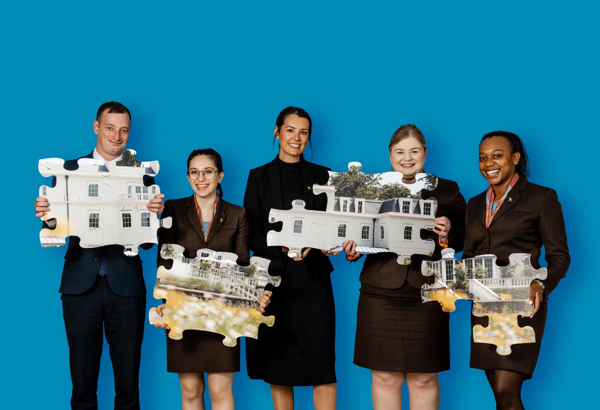 Group of employees holding puzzle pieces with photo of Coworth Park