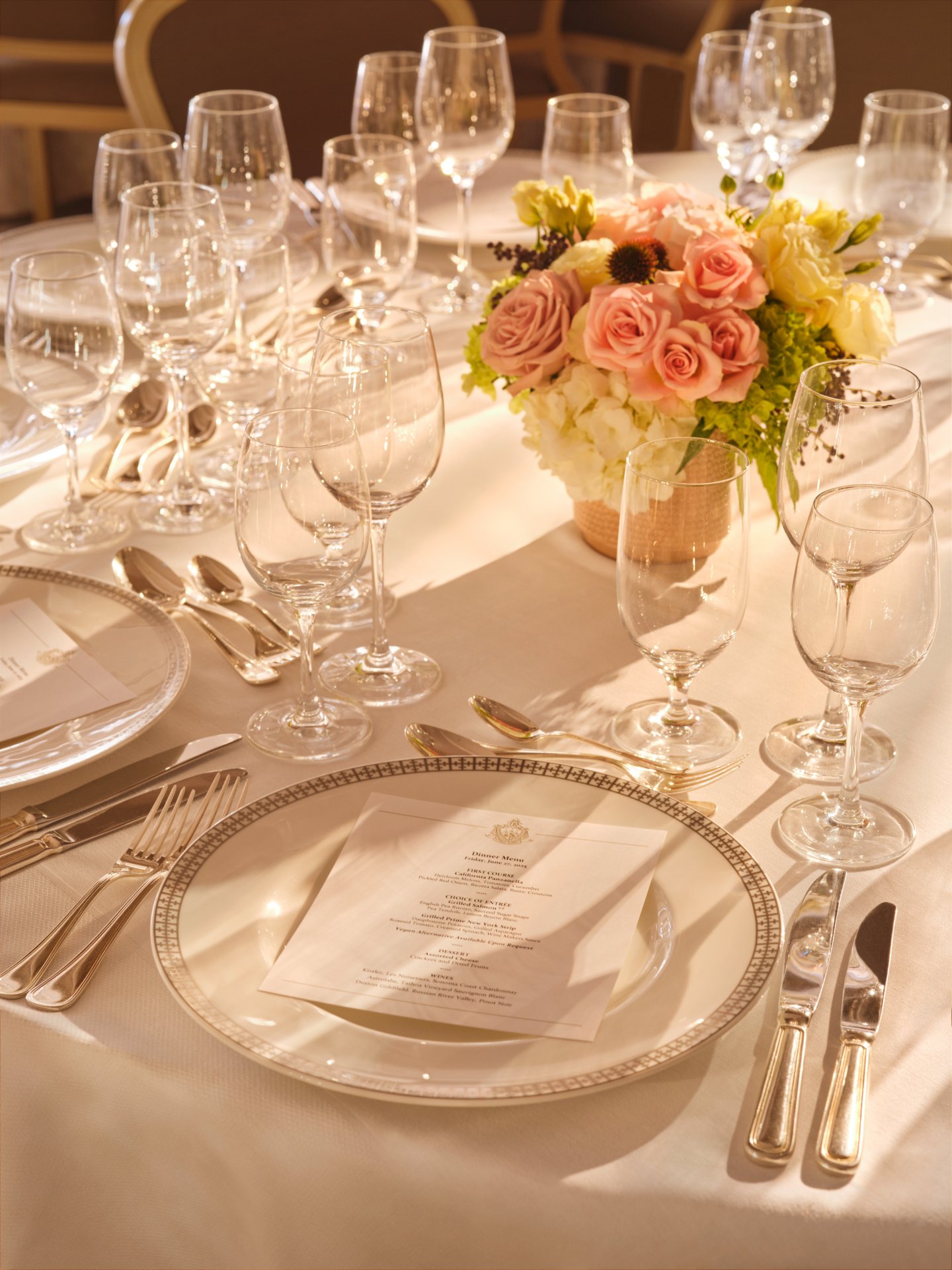 Elegant table set with floral centerpiece and multiple glasses, ready for a formal meal.