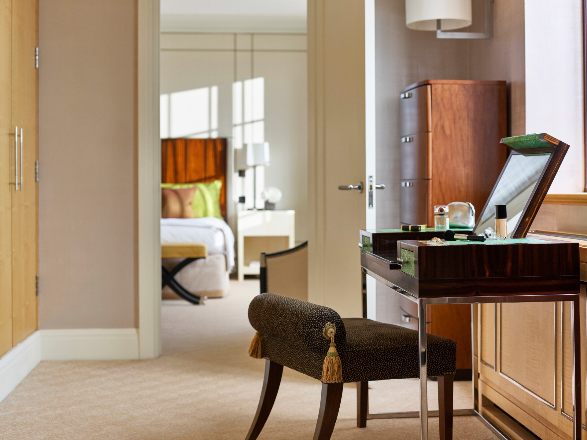 The Harlequin Penthouse Suite vanity table with make up on display and bedroom in background