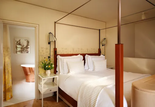 Four-poster bedroom with en-suite copper bathtub in the Farmer's Cottage suite at Coworth Park