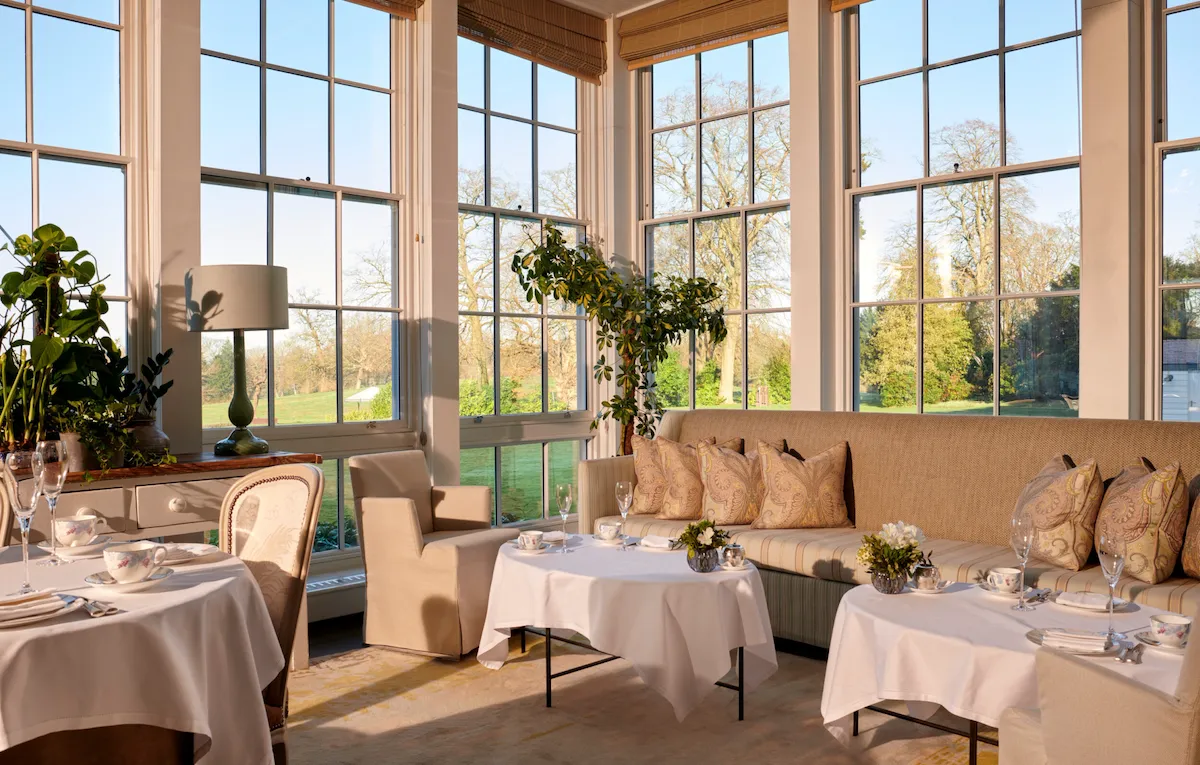 Coworth Park Drawing Room conservatory with champagne and cakes on table