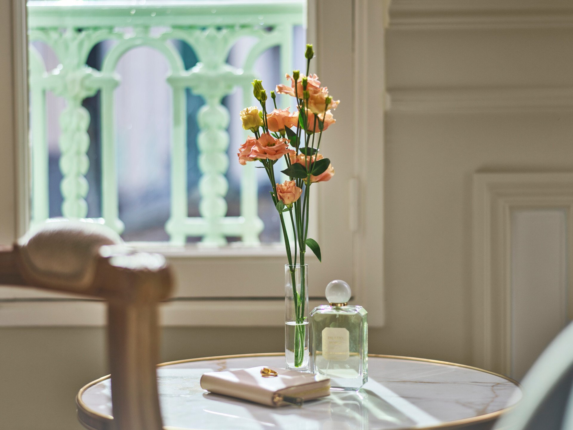 Flores, um frasco de perfume e uma bolsa colocados sobre uma mesa baixa de mármore num quarto superior. No Le Meurice, Paris.