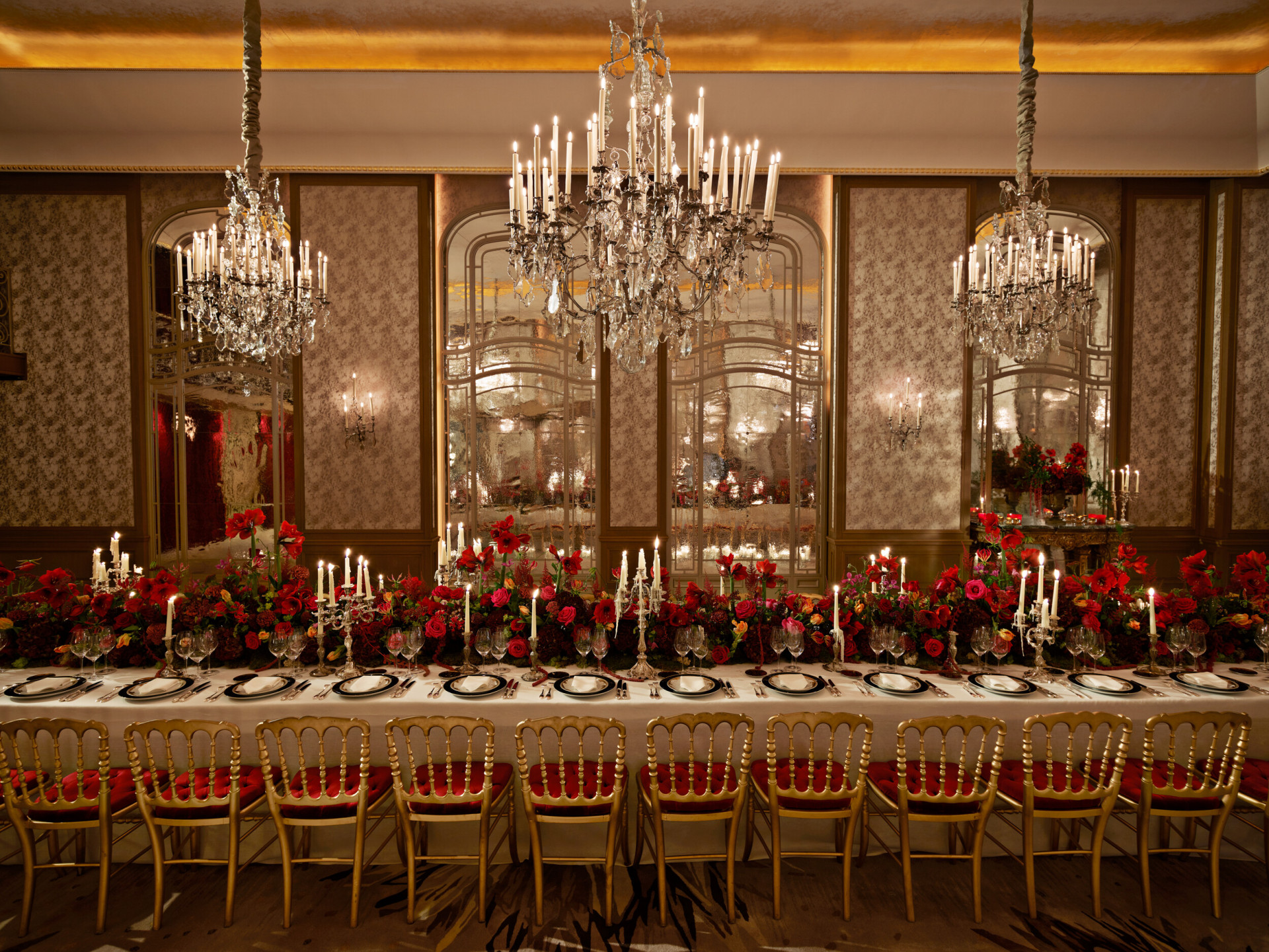 Jantar com uma mesa comprida e flores vermelhas captado no Salon Haute Couture, no Hôtel Plaza Athénée, Paris - Dorchester Collection.