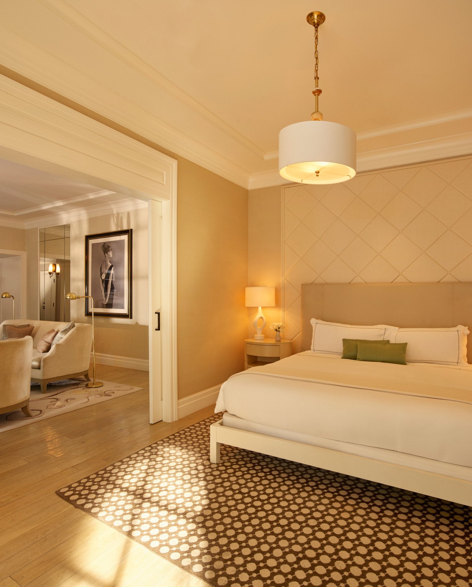 Bedroom facing the bed in the signature Grace Kelly Suite at Hotel Bel-Air with a glimpse of the adjacent Living Room area with a view of the portrait that's placed in the middle of the room. 