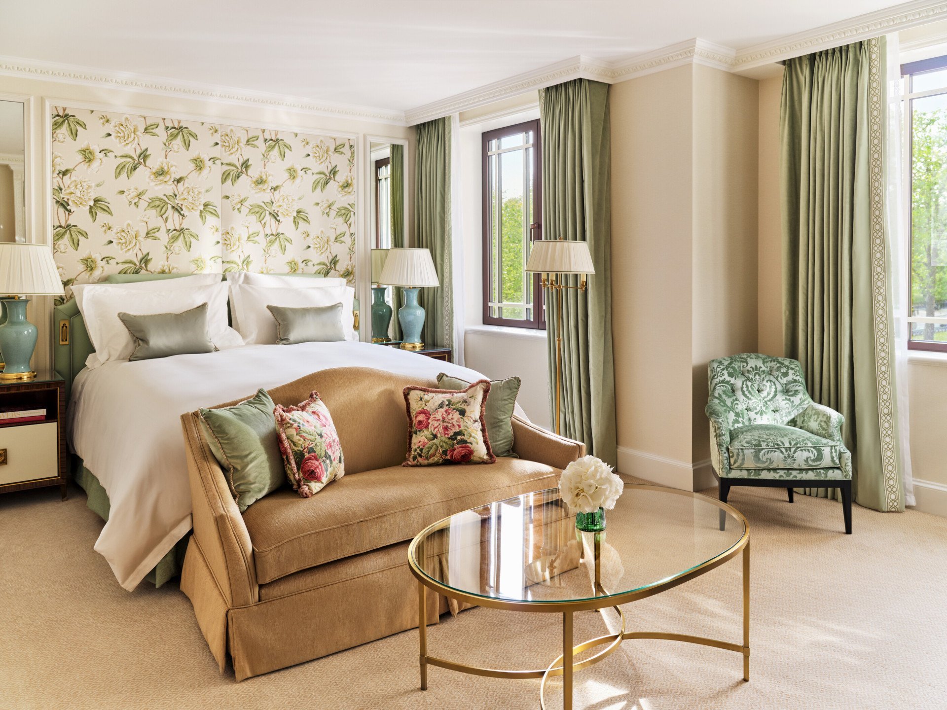 The Executive Park View Room at The Dorchester, showcasing botanical-patterned wall coverings, a king-sized bed, a comfortable seating area, green accent furnishings and large windows overlooking Hyde Park.
