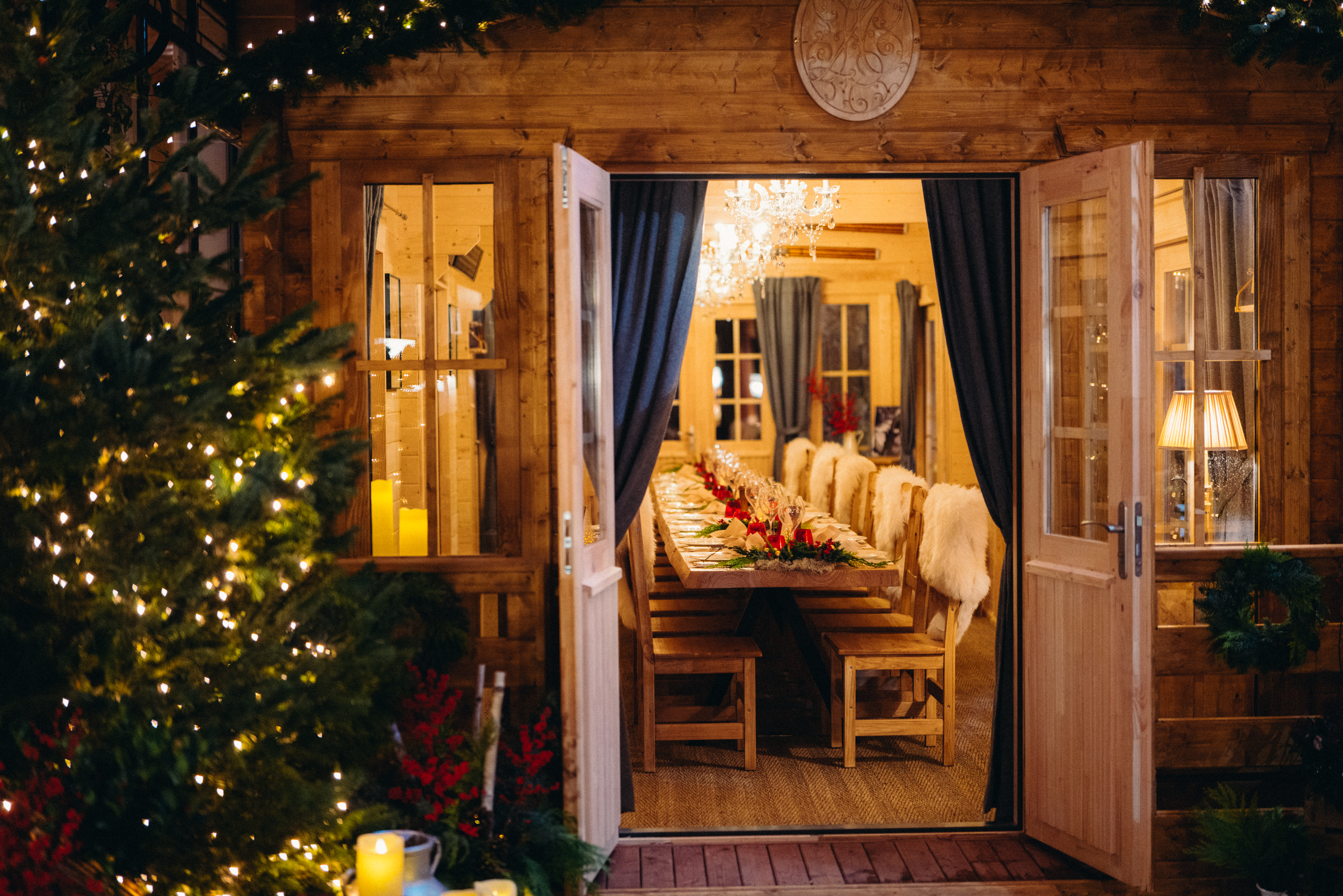 Le chalet du Plaza Athenée avec sa porte ouverte sur une table en bois dressée et ses chaises en bois