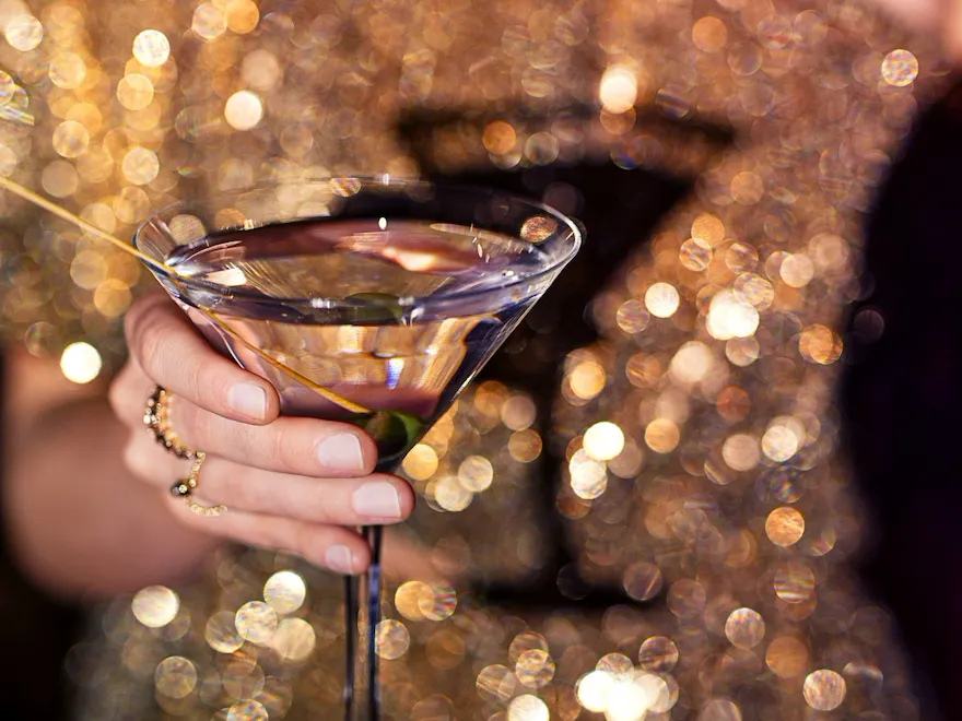 Women in a golden sequi dress holding a martini glass in her hand in the Salon Tuileries at Le Meurice, Paris - Dorchester Collection