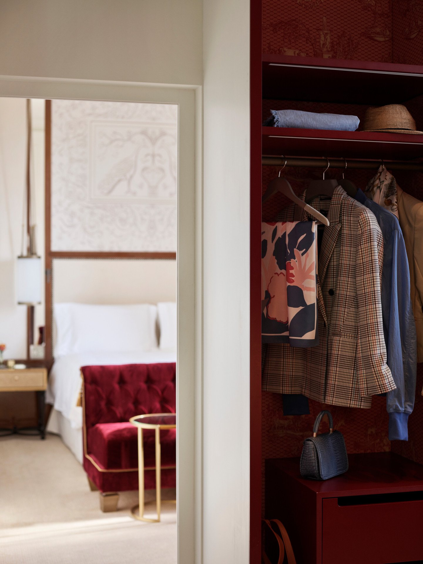 Cabina armadio con abiti appesi e borse e sullo sfondo camera da letto della Suite Dolce Vita a Hotel Eden Roma