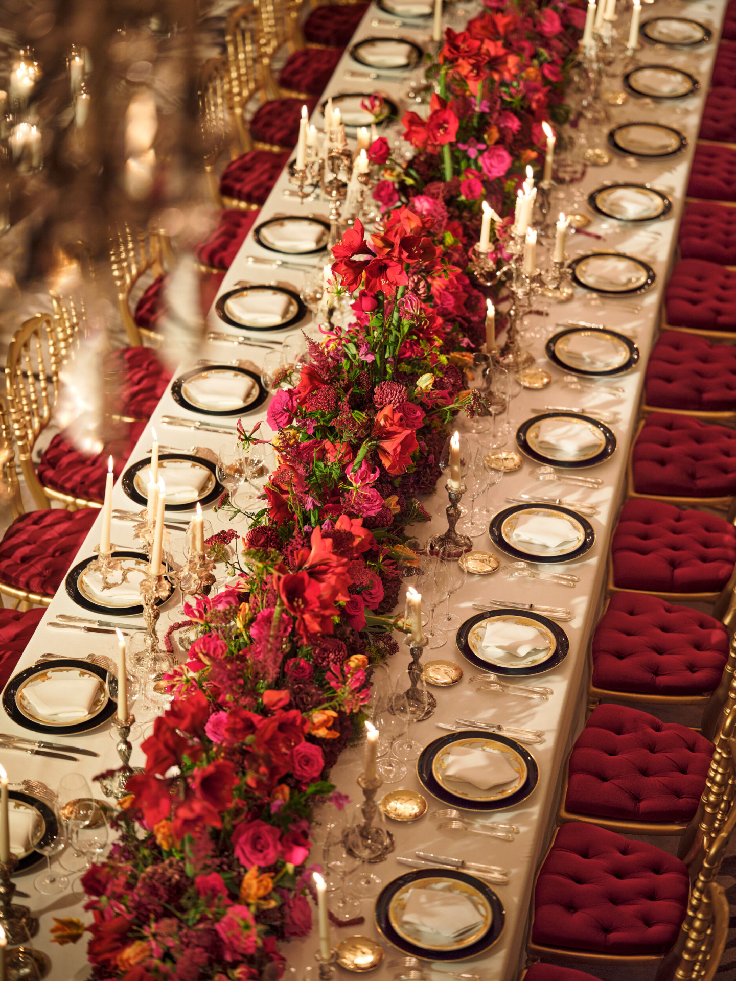 Dîner avec une longue table et des fleurs rouges capturées au Salon Haute Couture, à l’Hôtel Plaza Athénée, Paris - Dorchester Collection.