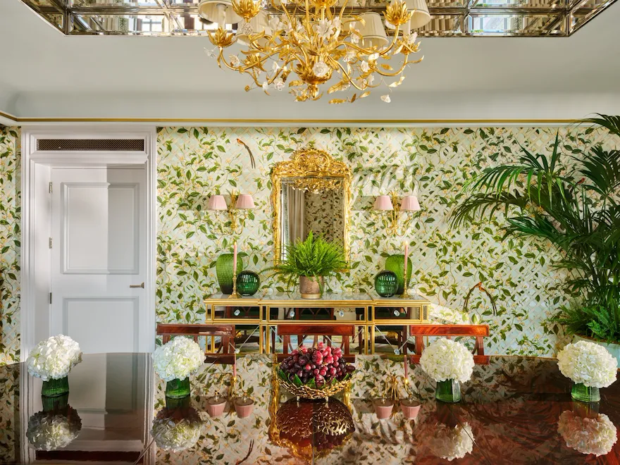 Elegant chandelier illuminates a lush themed dining room with floral wallpaper and lush greenery