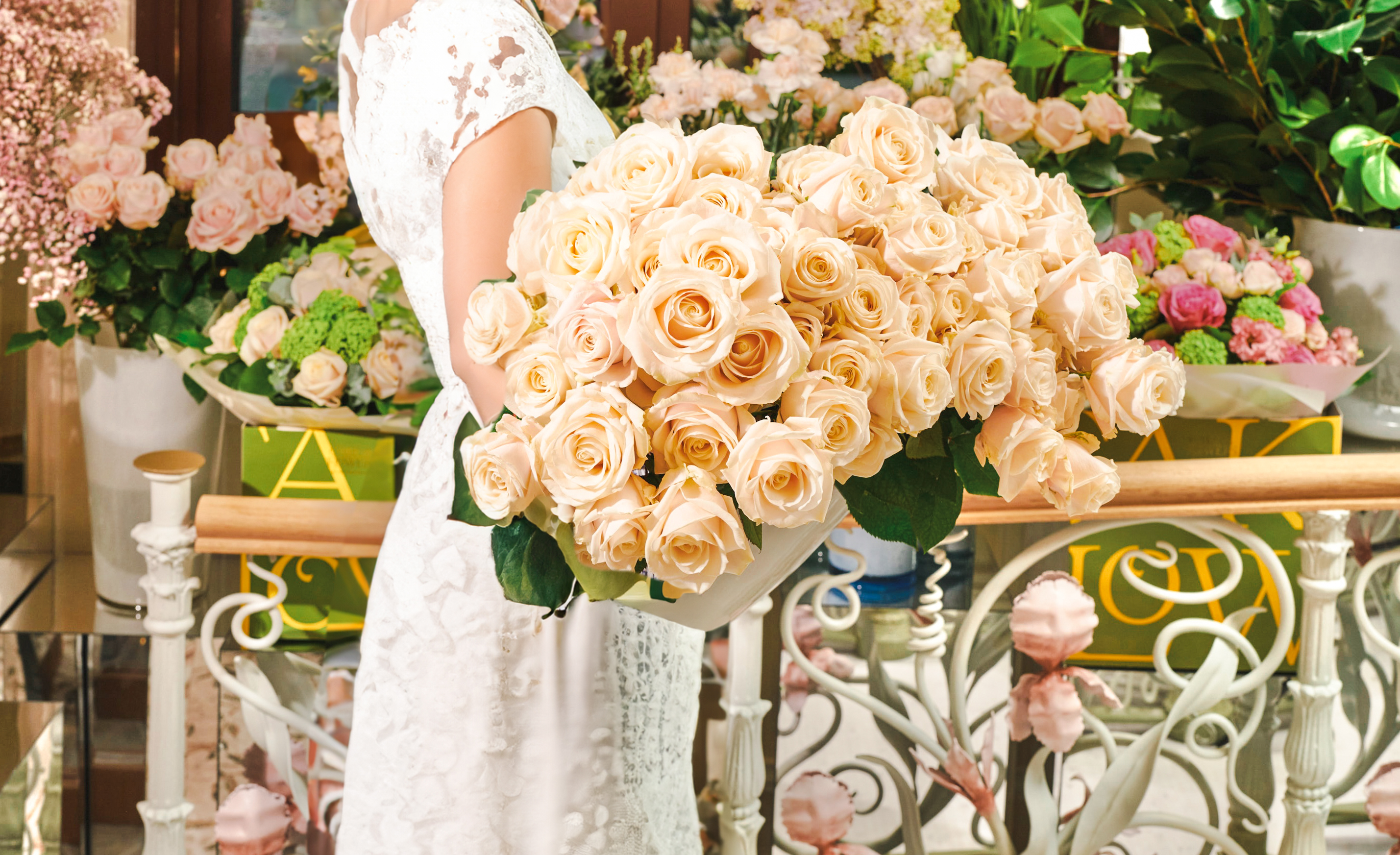 Woman holding large bouquet of soft blush Dorchester roses in Cake and Flowers boutique