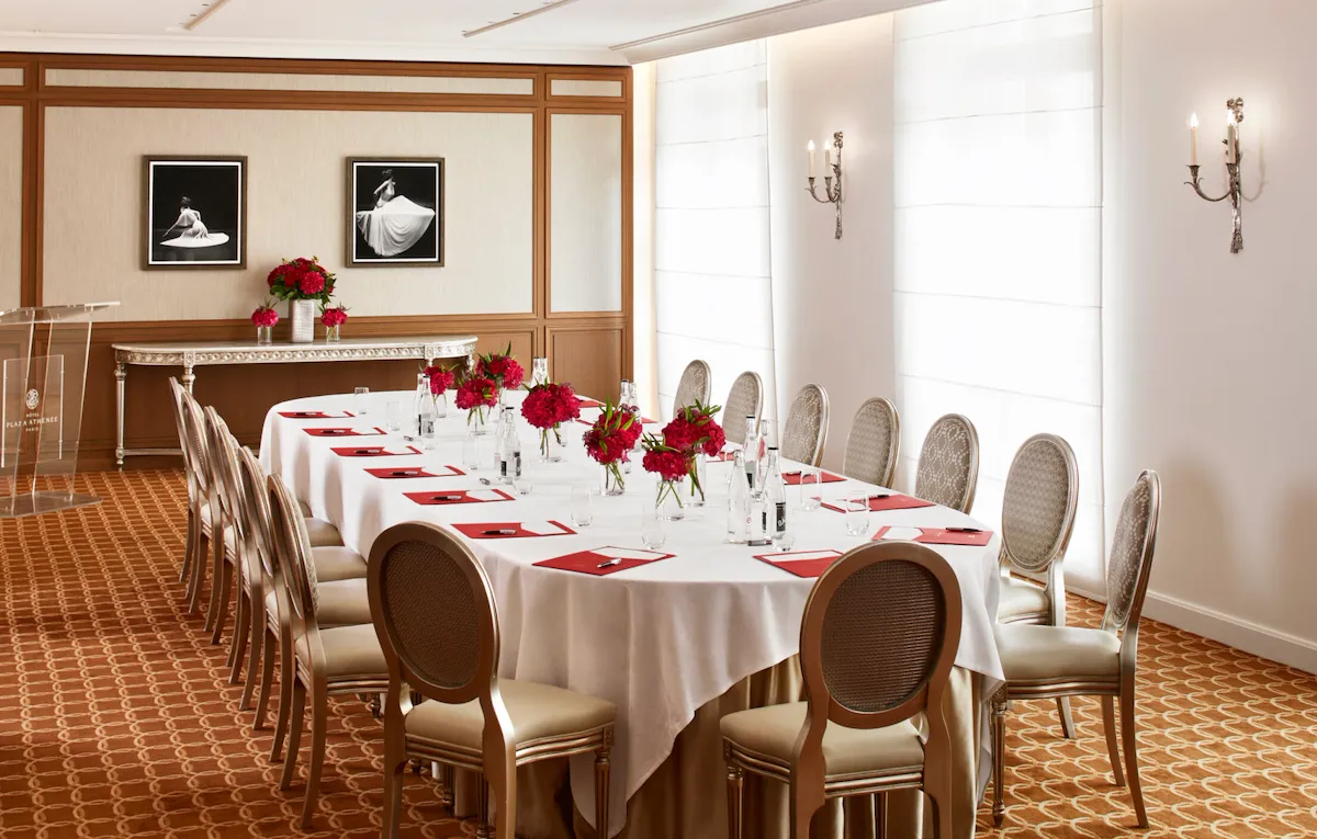 Salon création avec une table ovale de réunion dressée de fleurs et d'équipements pour écrire