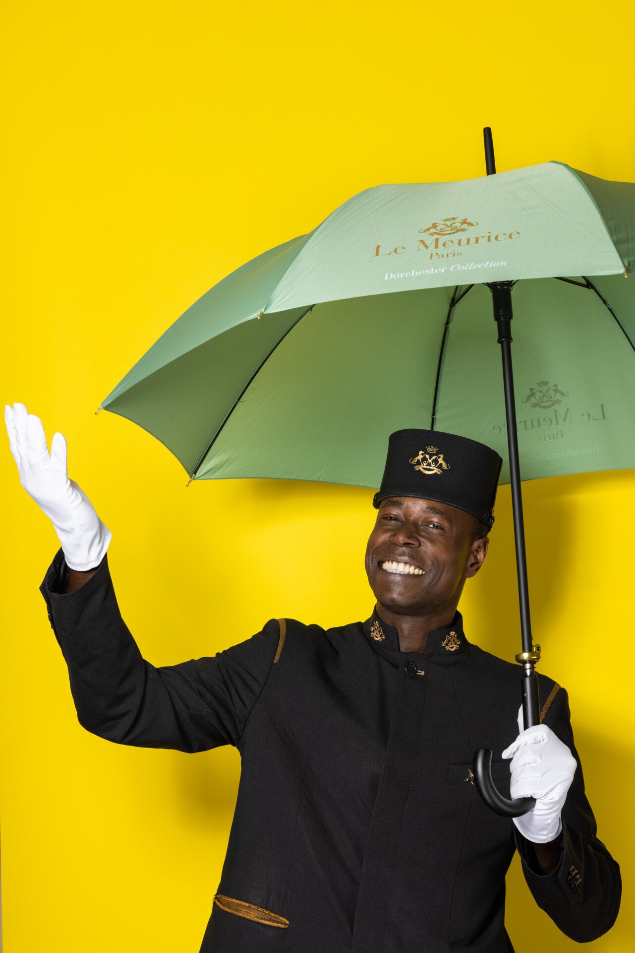 Gadio Mouhadji holding an umbrella against a yellow background
