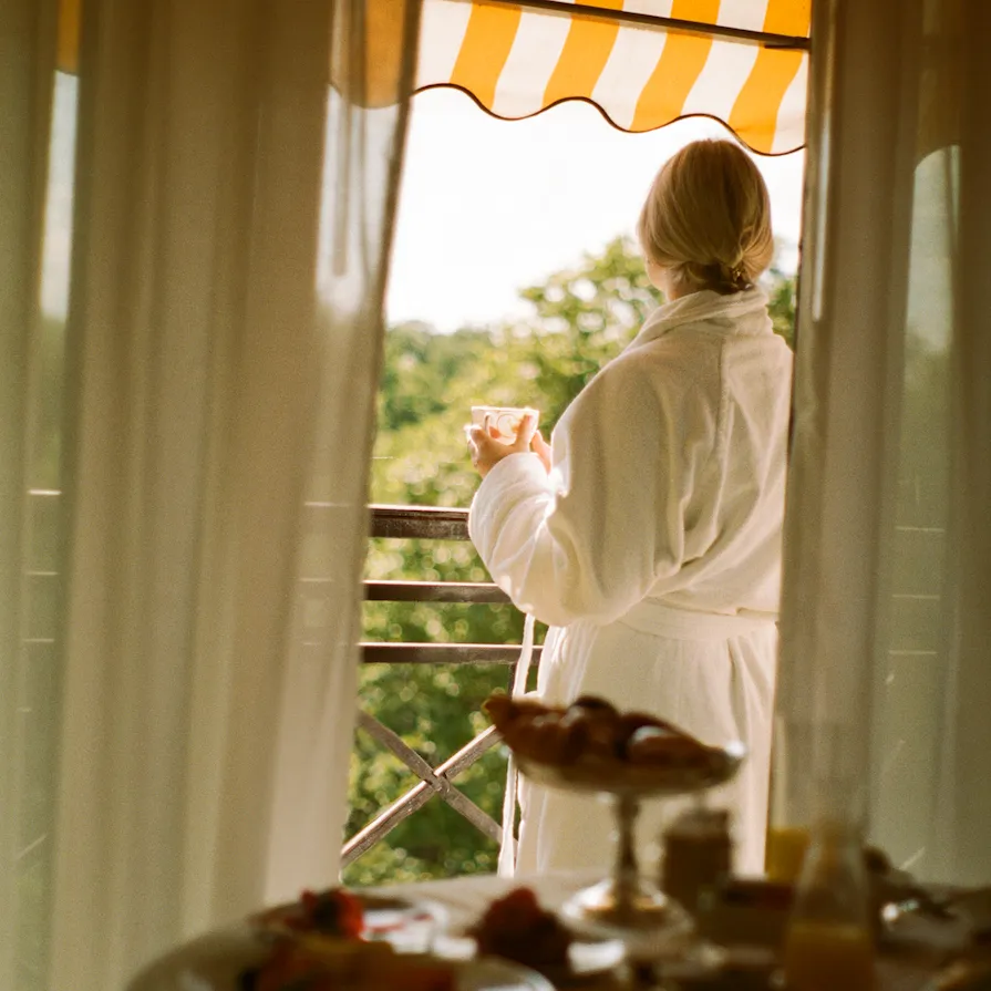 Woman on balcony looking out over the park in a robe