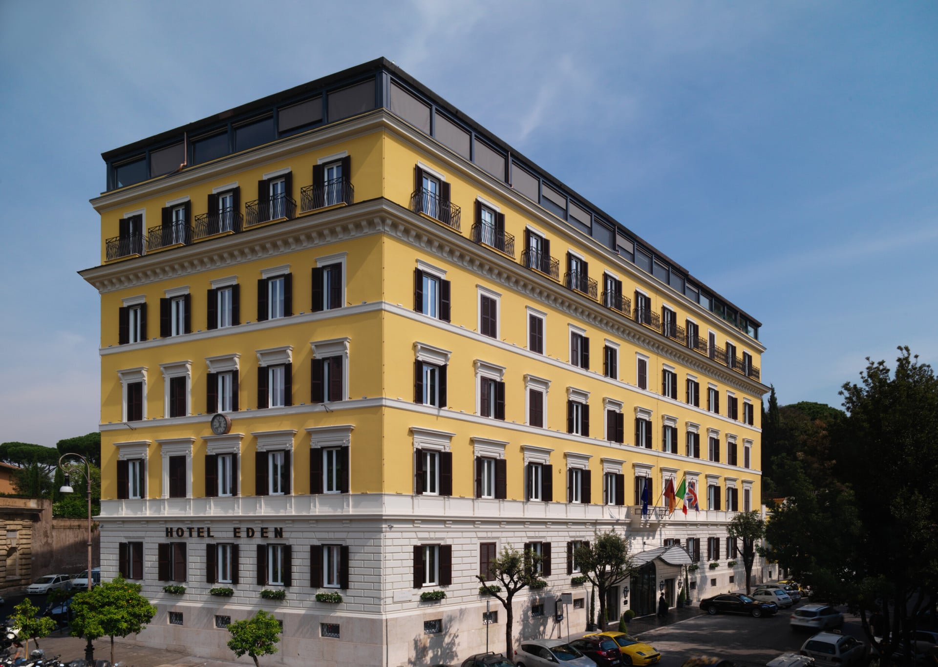 Corner view of Hotel Eden exterior yellow facade in a sunny day in Rome 