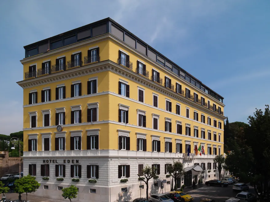 Corner view of Hotel Eden exterior yellow facade in a sunny day in Rome