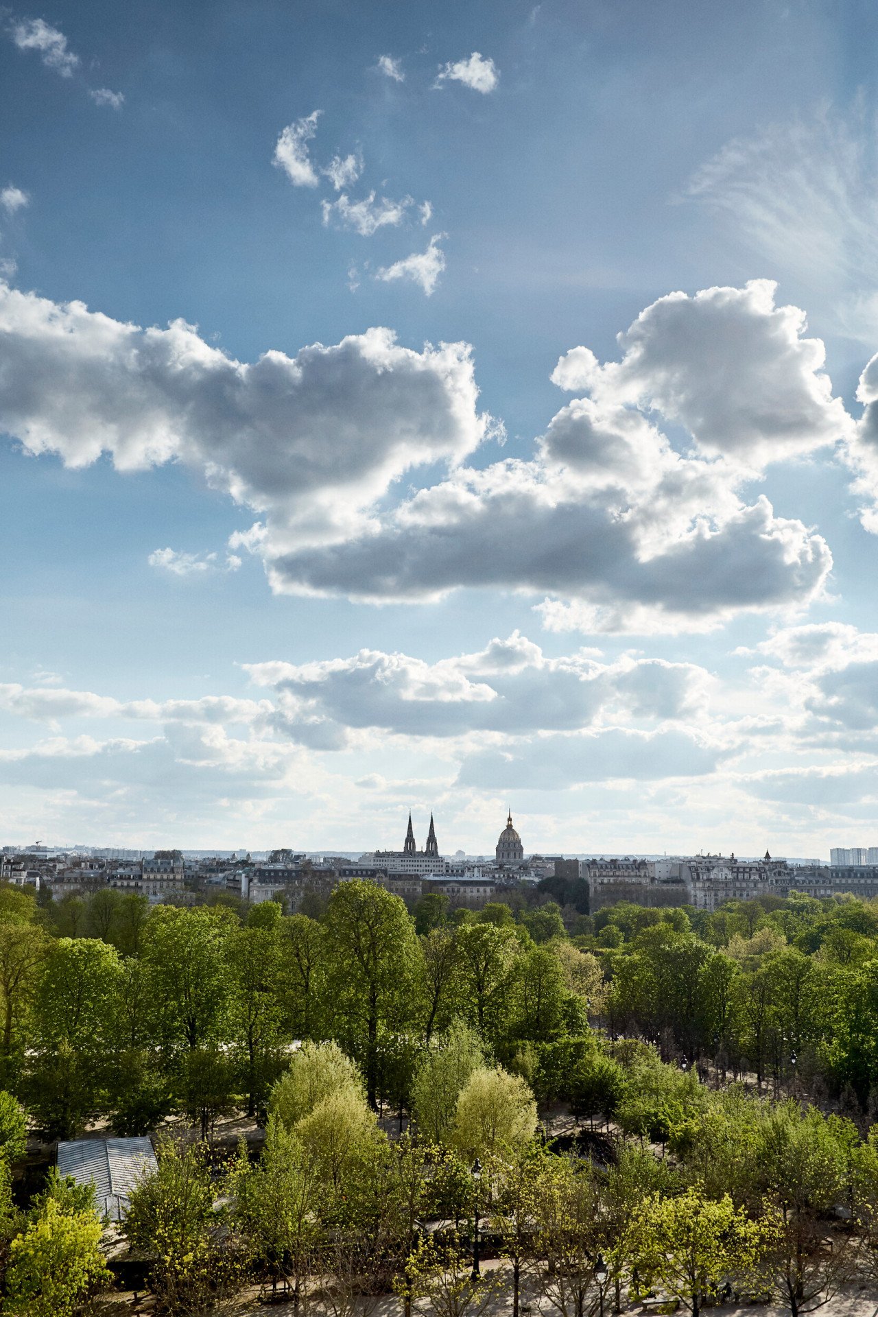 Vista de um quarto executivo do lado do parque, com o Jardim das Tulherias e a cidade ao fundo. No Le Meurice, Paris.